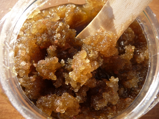 Jar of brown sugar scrub with a wooden stick in it 